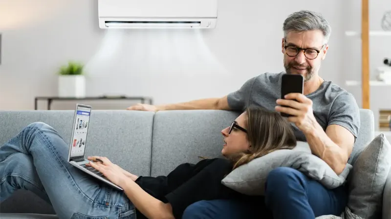 Couple On Sofa With Ductless Ac On Wall